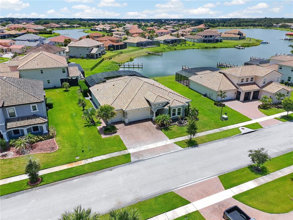 An aerial view of a suburban neighborhood featuring houses with tile roofs near a lake — 781 WINDLASS COURT, KISSIMMEE, FL
