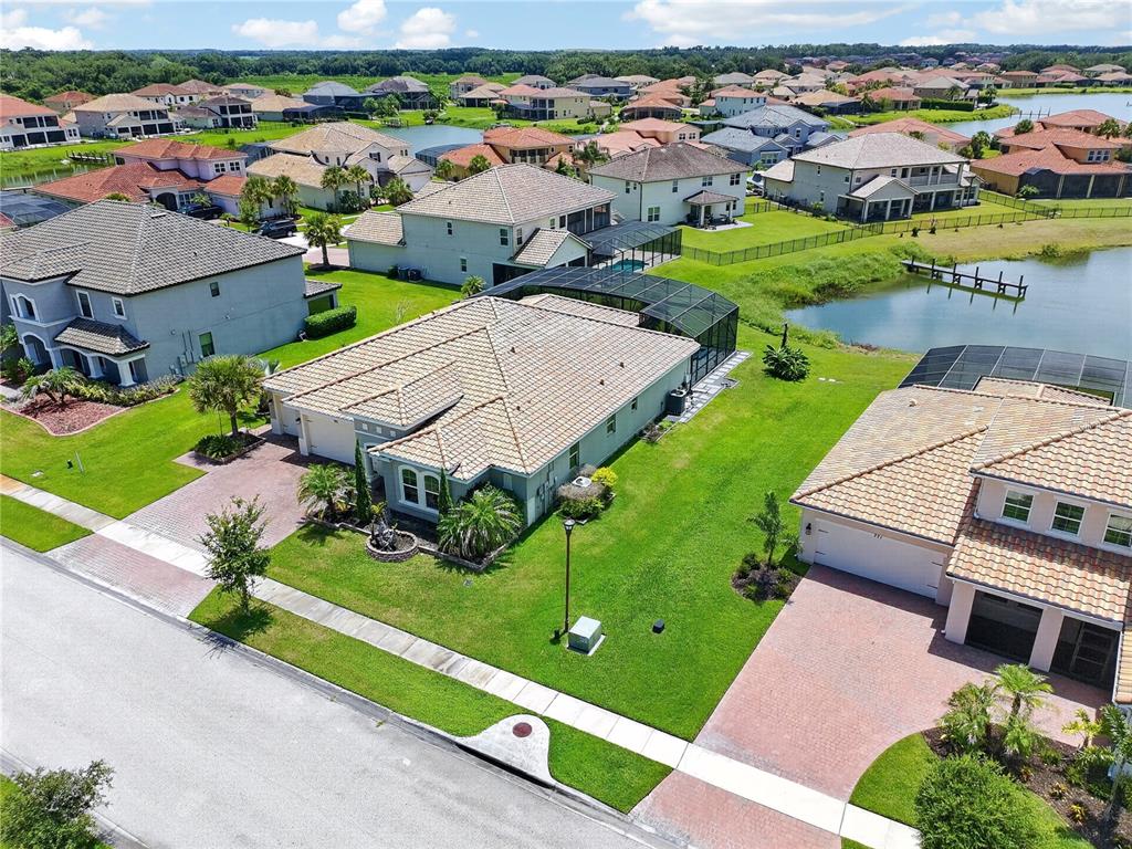 An aerial view shows suburban houses with tiled roofs, green lawns, and a small lake — 781 WINDLASS COURT, KISSIMMEE, FL