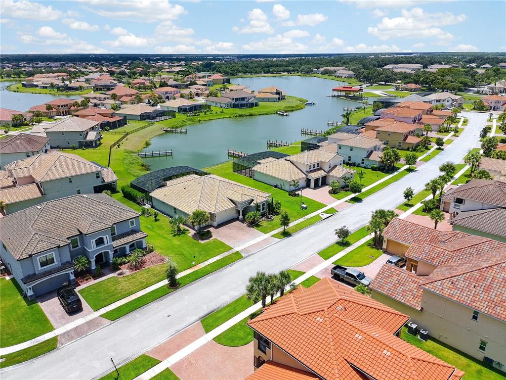 An aerial view of a suburban neighborhood featuring houses with tiled roofs near a lake — 781 WINDLASS COURT, KISSIMMEE, FL