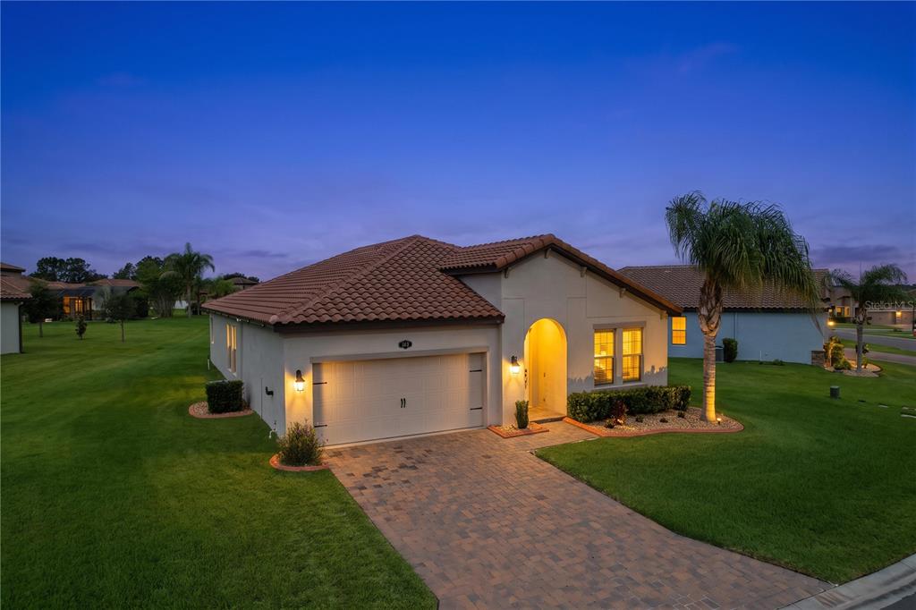 A single-story house with a tiled roof, two-car garage, and a paved driveway at dusk — 4125 PRIMA LAGO CIRCLE, LAKELAND, FL