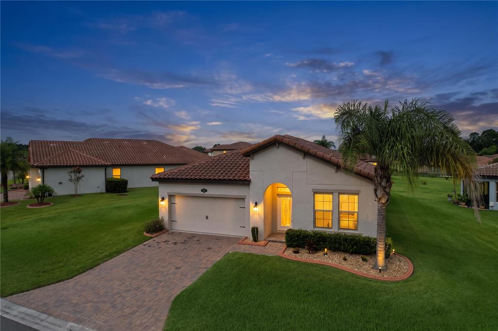 A single-story house with a tile roof, a paved driveway, and a palm tree at dusk — 4125 PRIMA LAGO CIRCLE, LAKELAND, FL