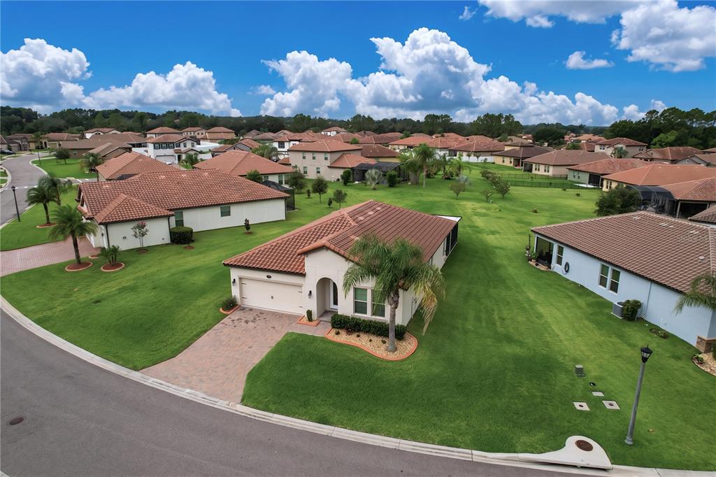 An aerial view shows a suburban neighborhood with single-story homes featuring tiled roofs and lawns — 4125 PRIMA LAGO CIRCLE, LAKELAND, FL