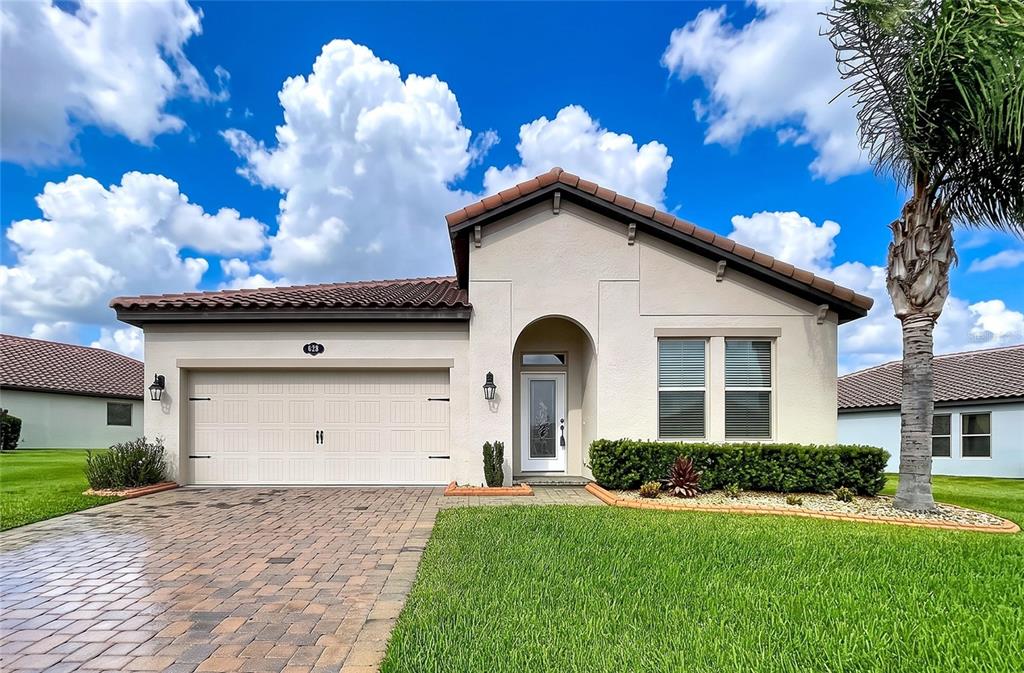 A single-story house with a beige stucco exterior, a tiled roof, and a paved driveway — 4125 PRIMA LAGO CIRCLE, LAKELAND, FL