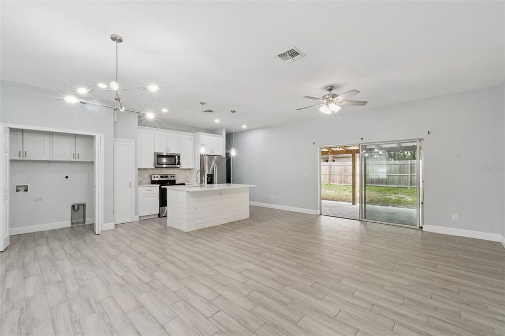 An open-concept kitchen and living area features white cabinetry, a center island, and tile flooring — 1221 3RD STREET, ORANGE CITY, FL