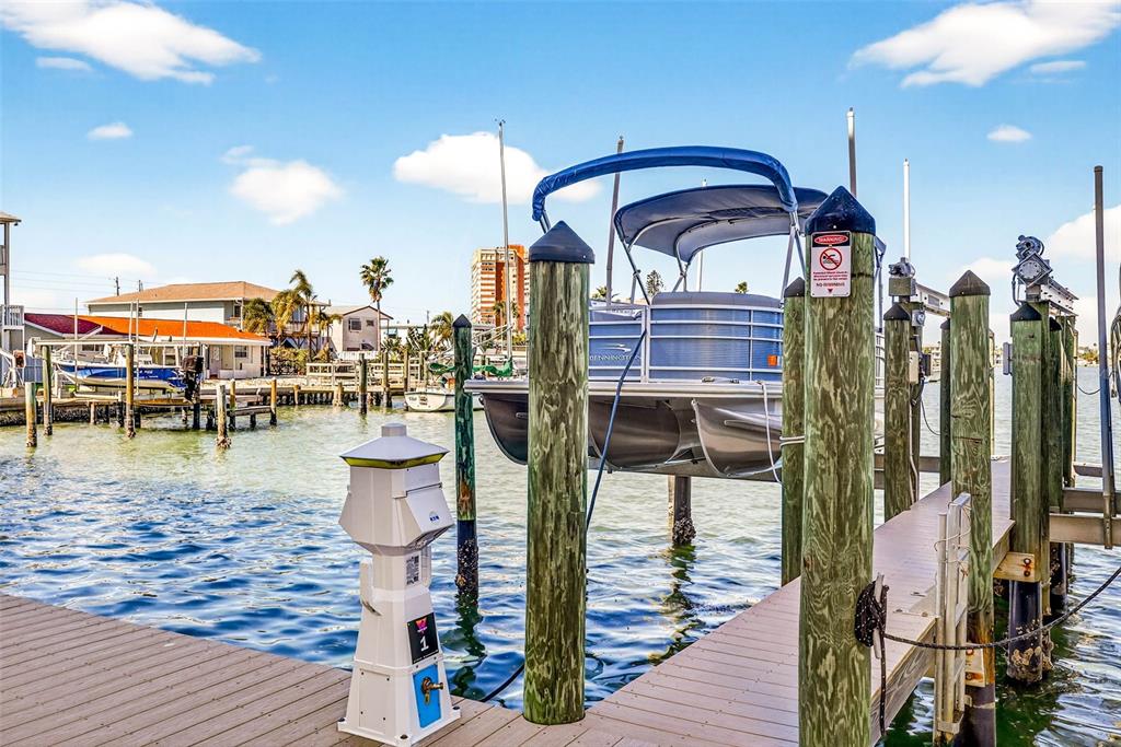 A pontoon boat is lifted on a mechanical hoist at a wooden boat dock — 17717 GULF BOULEVARD UNIT 401, REDINGTON SHORES, FL
