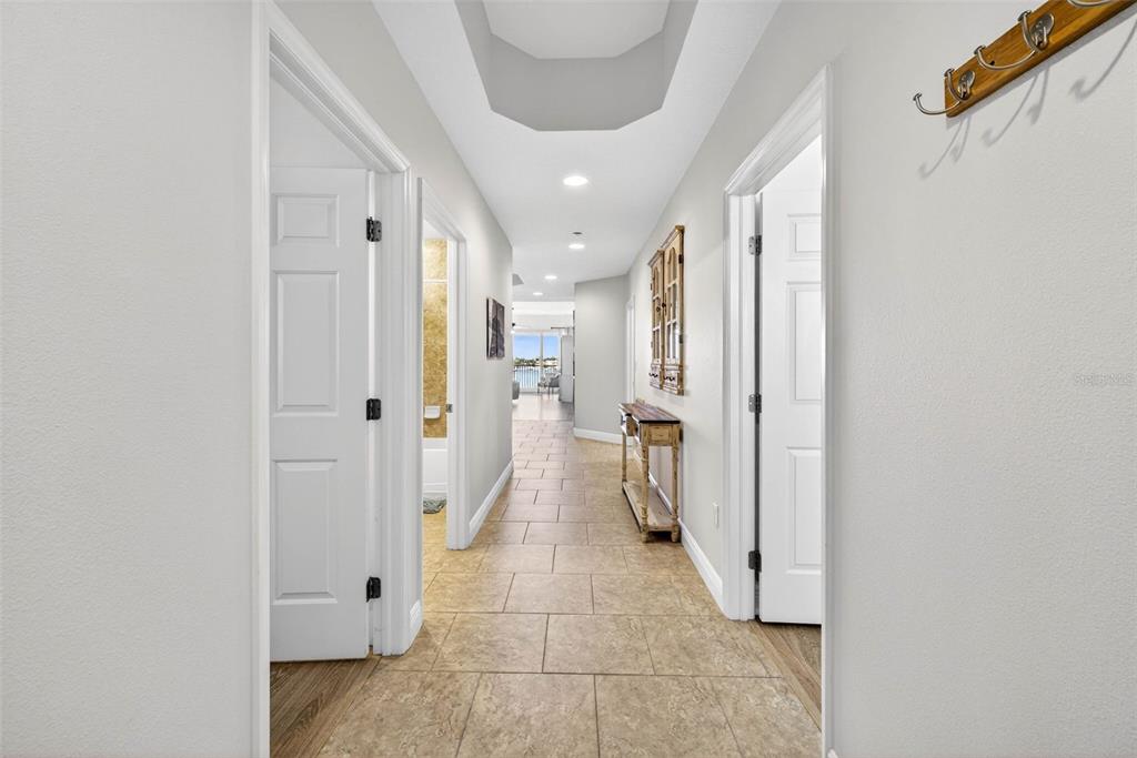 A tiled hallway features white doors, a wooden console table, and a view of water — 17717 GULF BOULEVARD UNIT 401, REDINGTON SHORES, FL