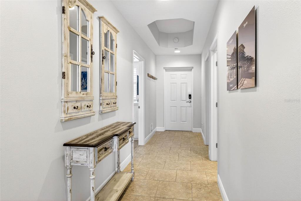 A hallway features a rustic console table, wall mirrors, tile flooring, and a white door — 17717 GULF BOULEVARD UNIT 401, REDINGTON SHORES, FL