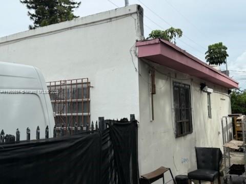 The exterior of a white building features a pink roof overhang and metal window security bars — 11628 NW 7th Ave, Miami FL 33168, MIAMI, FL