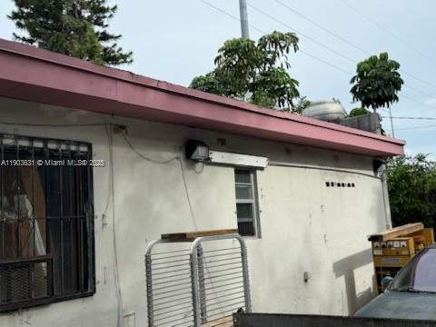 The exterior of a building shows a white stucco wall, a pink roofline, and a window with security bars — 11628 NW 7th Ave, Miami FL 33168, MIAMI, FL