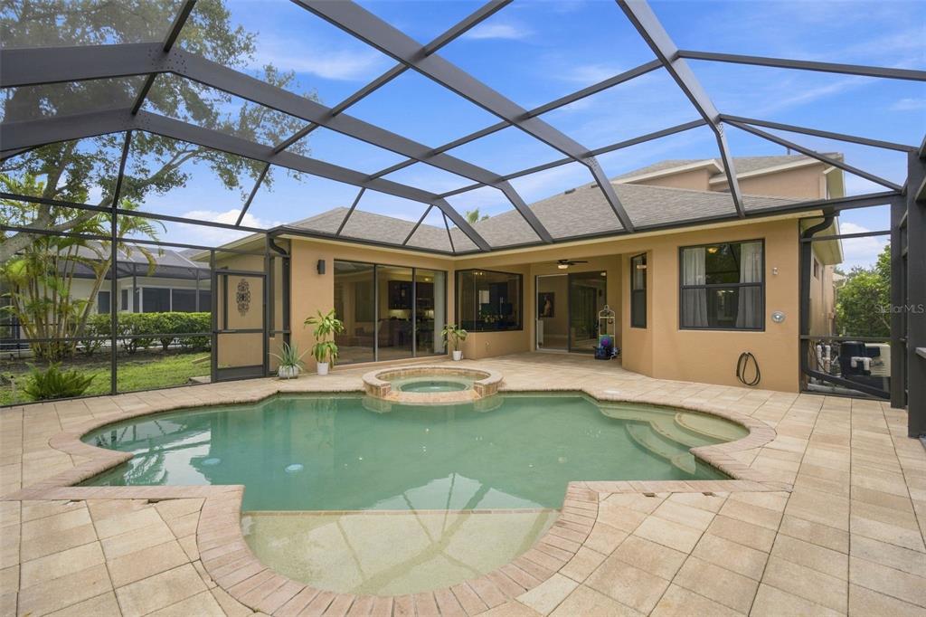 A screened-in patio features a swimming pool with an integrated spa and paver decking — 235 DAHLIA COURT, BRADENTON, FL