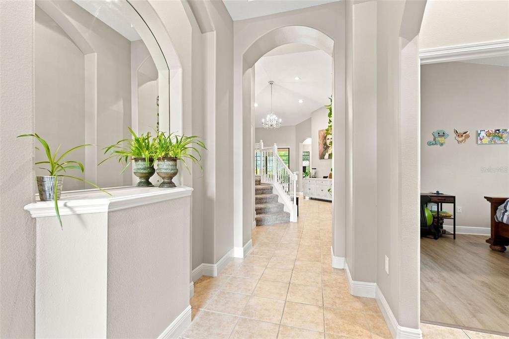A tiled entryway leads to a staircase and a hallway with arched architectural details — 235 DAHLIA COURT, BRADENTON, FL