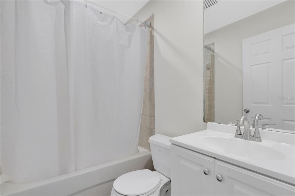 A bathroom features a white vanity, a toilet, and a shower-tub combination with a curtain — 3450 PARK AVENUE, INDIAN LAKE ESTATES, FL