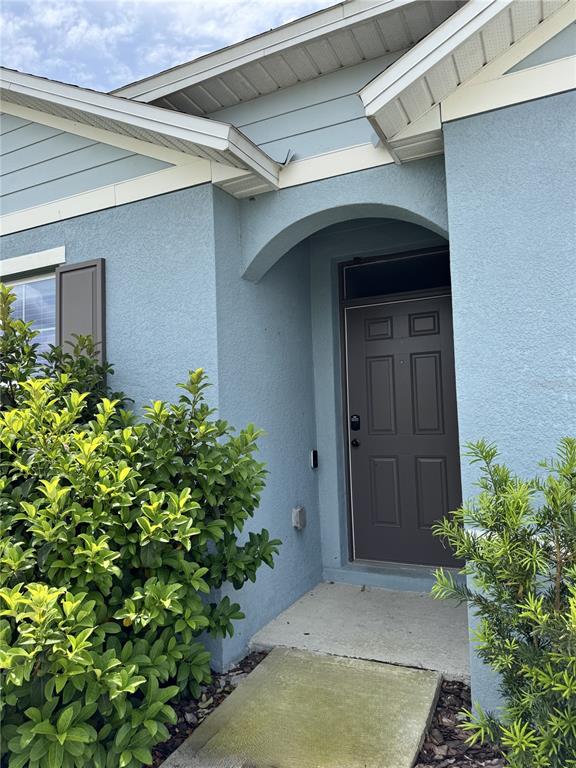 The exterior of a blue house features a recessed front door and green landscaping — 1325 WINTER GRAY CIRCLE, DELTONA, FL