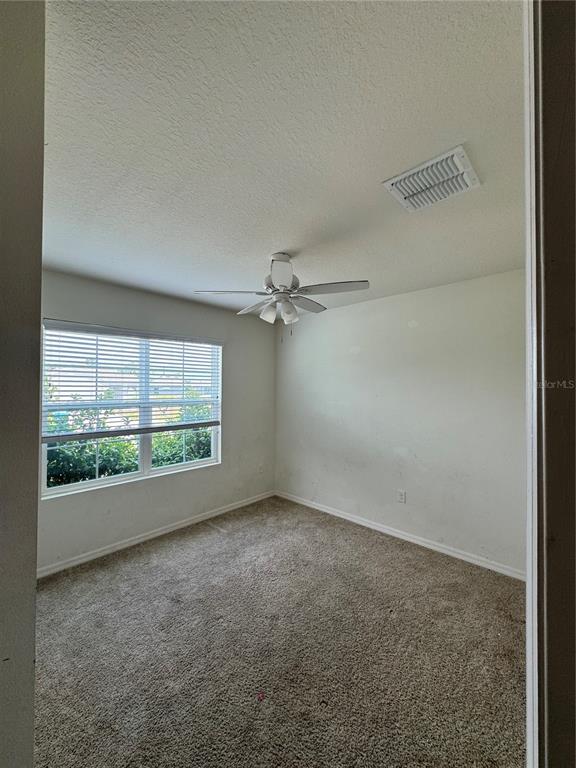 An empty bedroom with beige carpet, a ceiling fan, and a window with white blinds — 1325 WINTER GRAY CIRCLE, DELTONA, FL