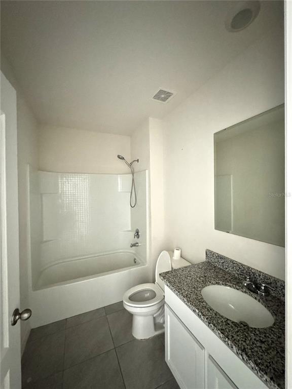 A bathroom features a white tub-shower combo, a toilet, and a granite-topped vanity — 1325 WINTER GRAY CIRCLE, DELTONA, FL