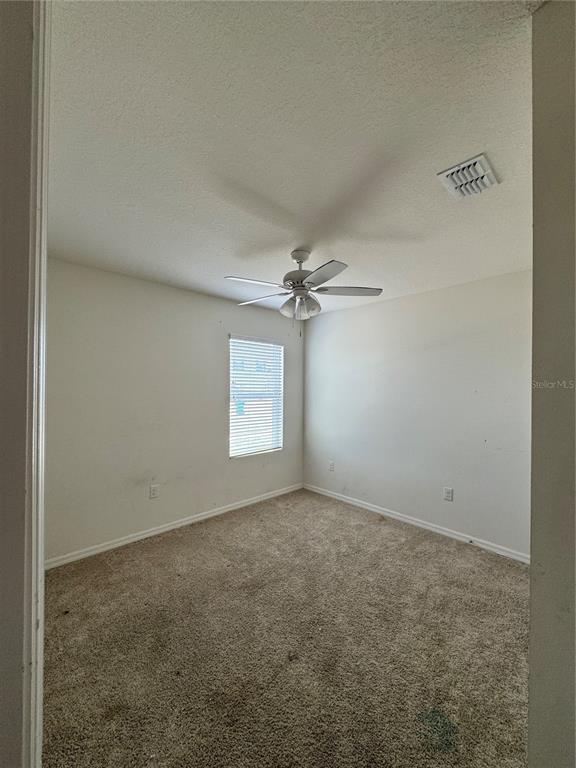 An empty bedroom features beige carpet, white walls, a ceiling fan, and a single window — 1325 WINTER GRAY CIRCLE, DELTONA, FL