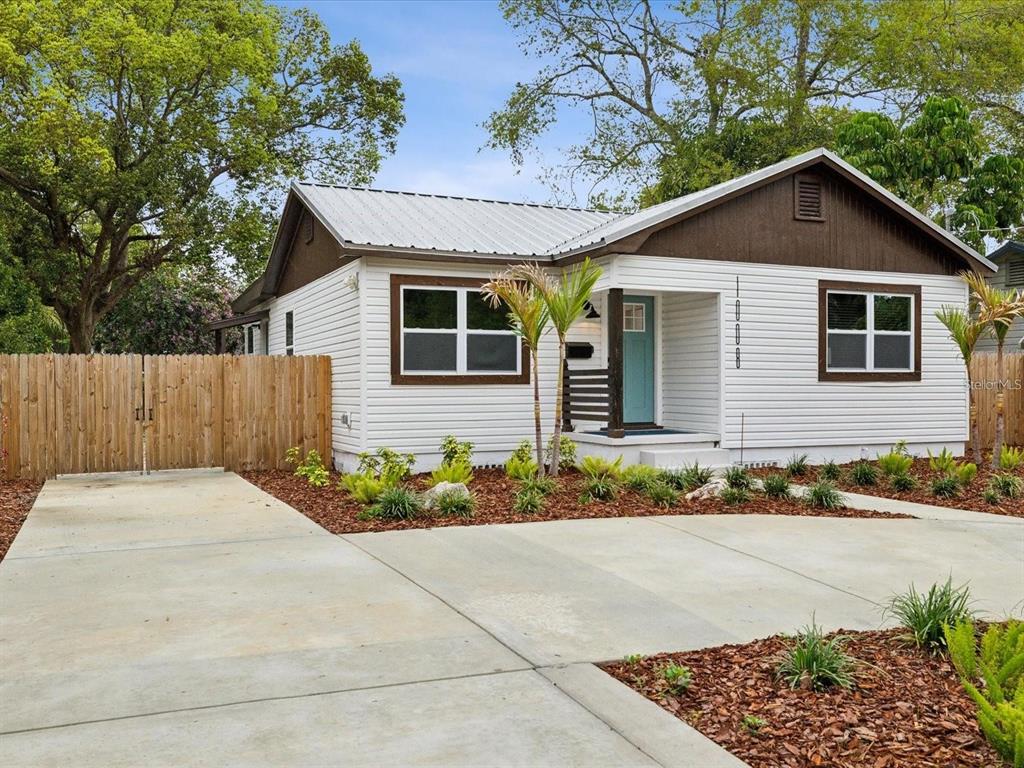 A single-story house with white siding, a metal roof, and a concrete driveway — 1008 E NORFOLK STREET, TAMPA, FL