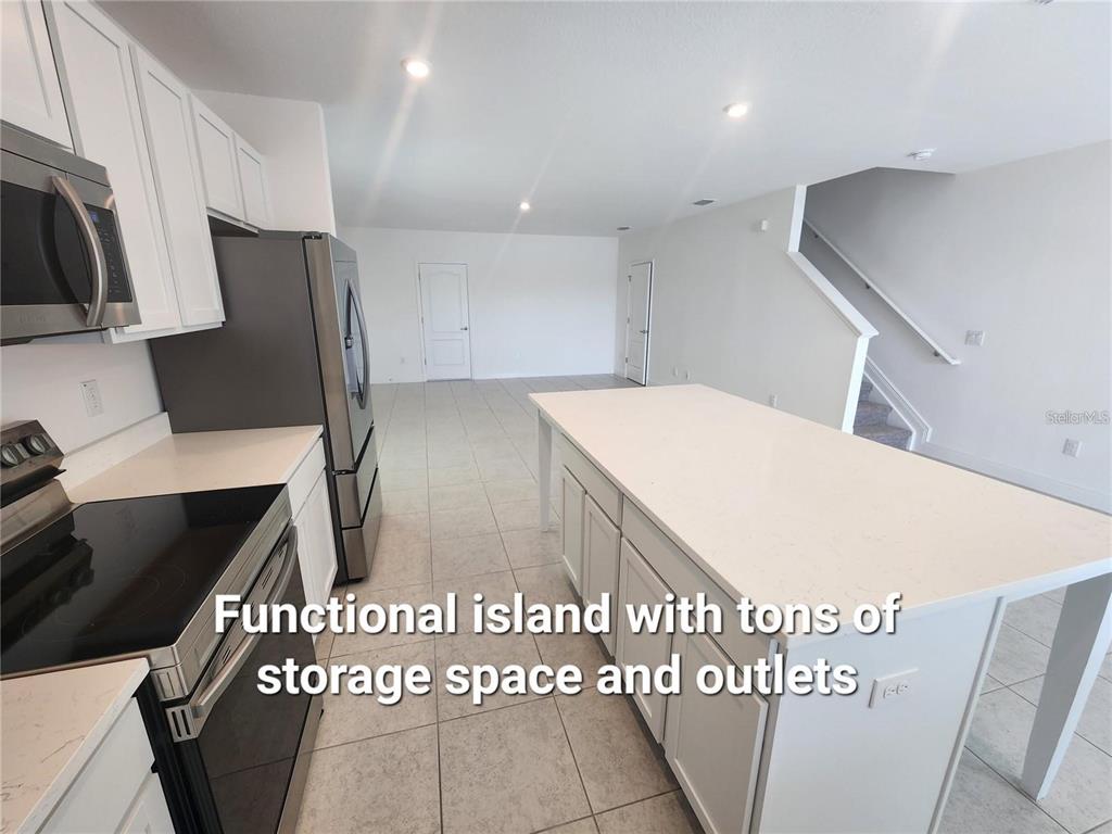 A kitchen features white cabinets, stainless steel appliances, and a large central island — 32118 POND APPLE BEND, SAN ANTONIO, FL