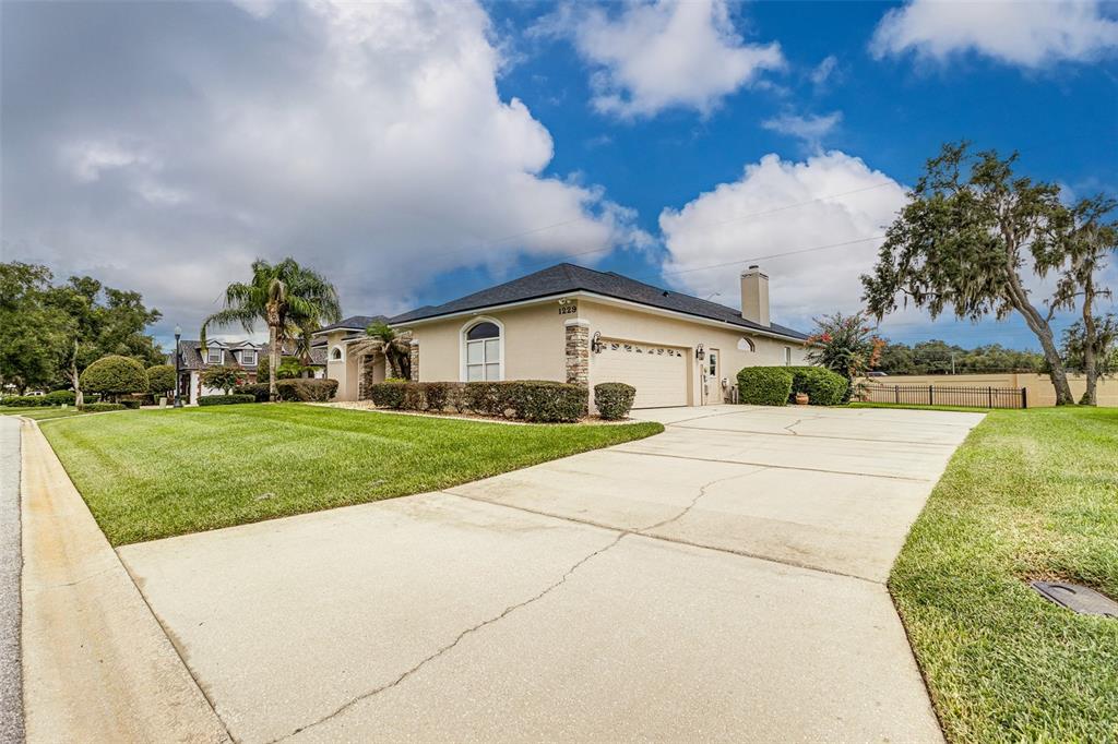 A single-story house with a beige exterior, a two-car garage, and a concrete driveway — 1229 LAKE DEESON WOODS LANE, LAKELAND, FL