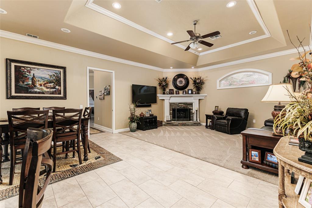 A living room with a fireplace, ceiling fan, and adjacent dining area with tile flooring — 1229 LAKE DEESON WOODS LANE, LAKELAND, FL