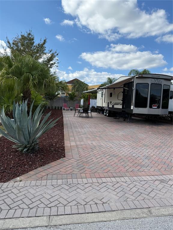 A paved driveway features a parked RV, outdoor seating, and a large agave plant — 6731 AMANDA VISTA CIRCLE, LAND O LAKES, FL