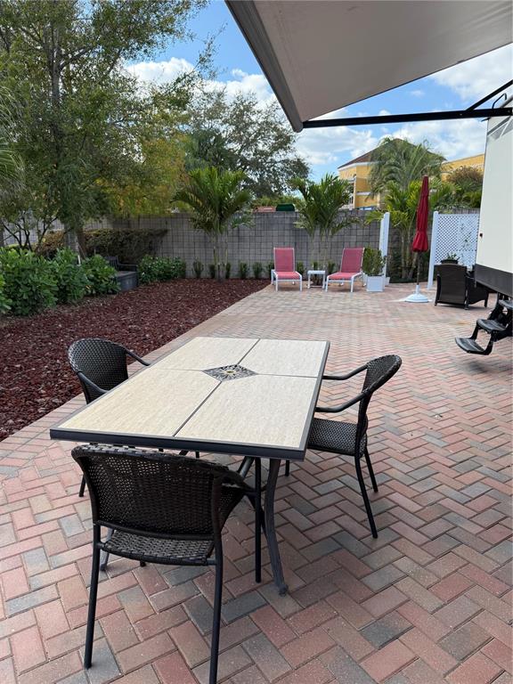 A patio features a dining set on brick pavers with a view of palm trees — 6731 AMANDA VISTA CIRCLE, LAND O LAKES, FL