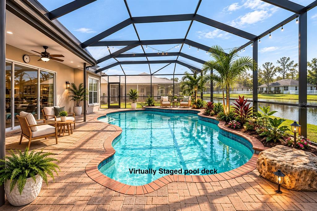 A screened-in pool patio features brick pavers, lounge furniture, and a view of a lake — 5128 HARTWELL LOOP, LAND O LAKES, FL