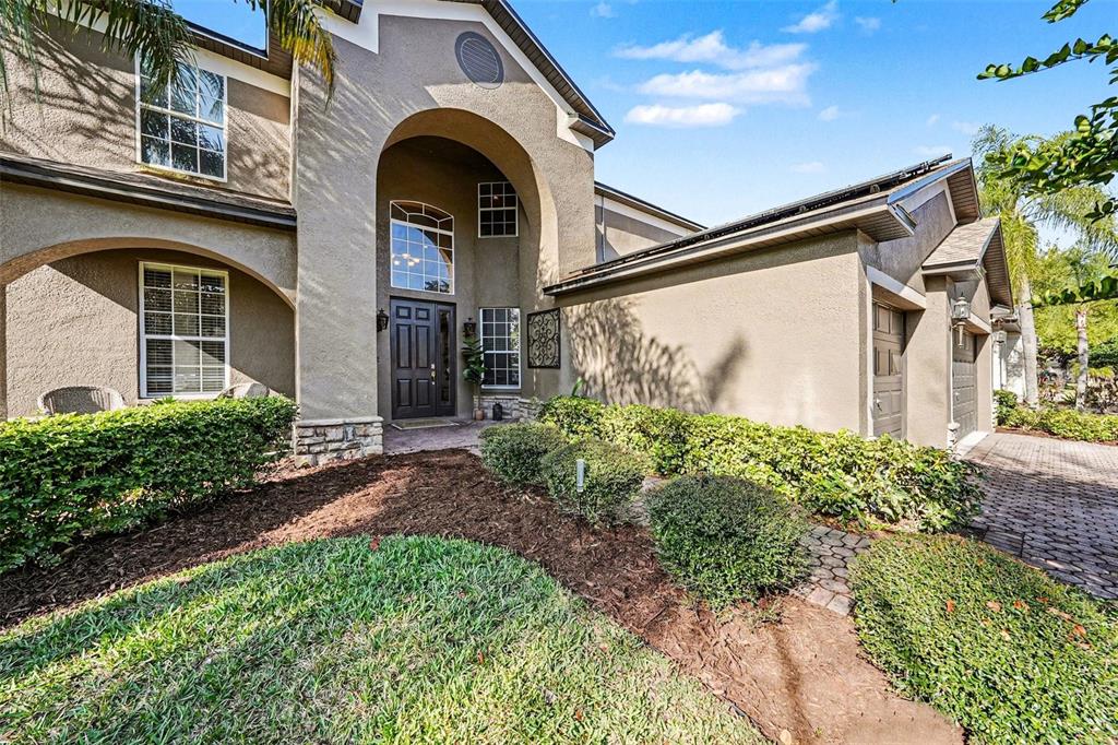 A two-story house with a stucco exterior, arched entryway, and a paved driveway — 5128 HARTWELL LOOP, LAND O LAKES, FL