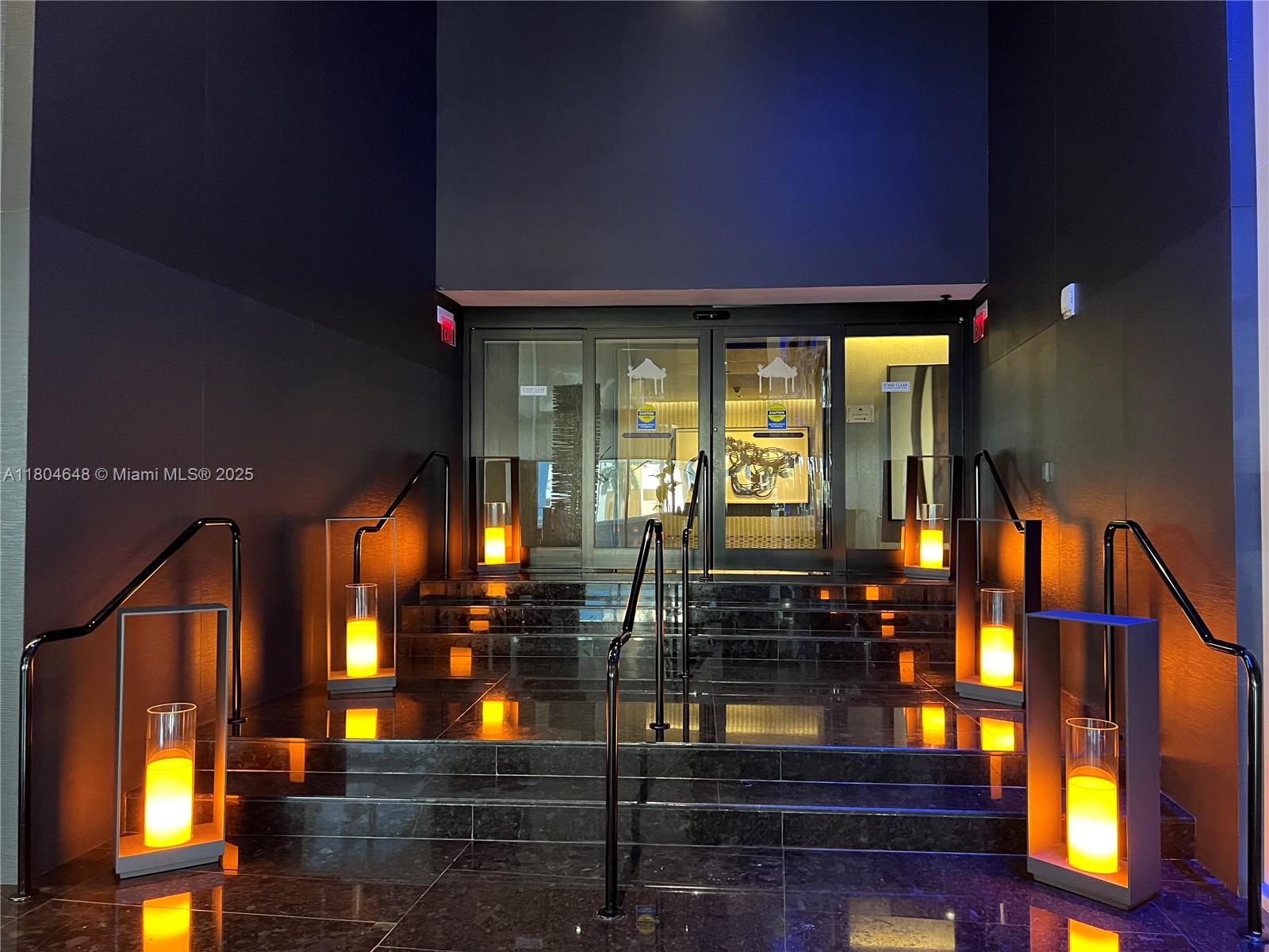 A set of dark marble stairs leads to glass entrance doors flanked by illuminated lanterns — 1800 S Ocean Dr # 2006, Hallandale Beach FL 33009, HALLANDALE BEACH, FL