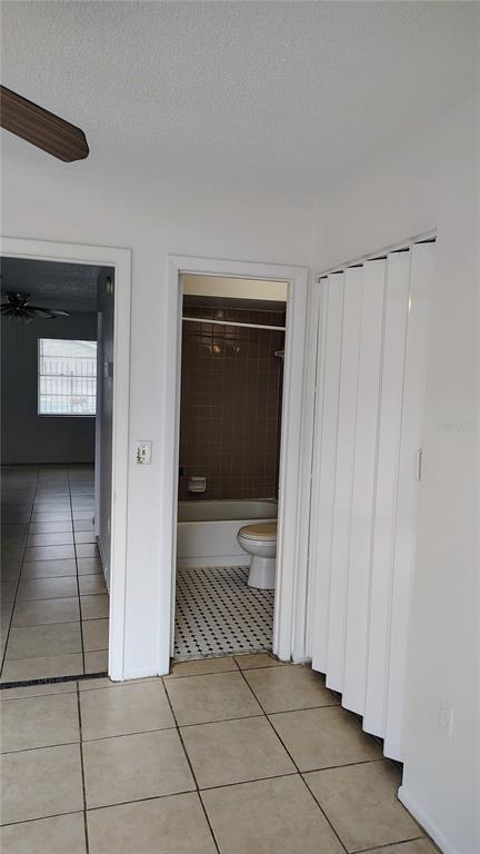 A view of a bathroom with a tub and toilet, adjacent to a tiled hallway — 6 LAKE VILLA WAY, KISSIMMEE, FL