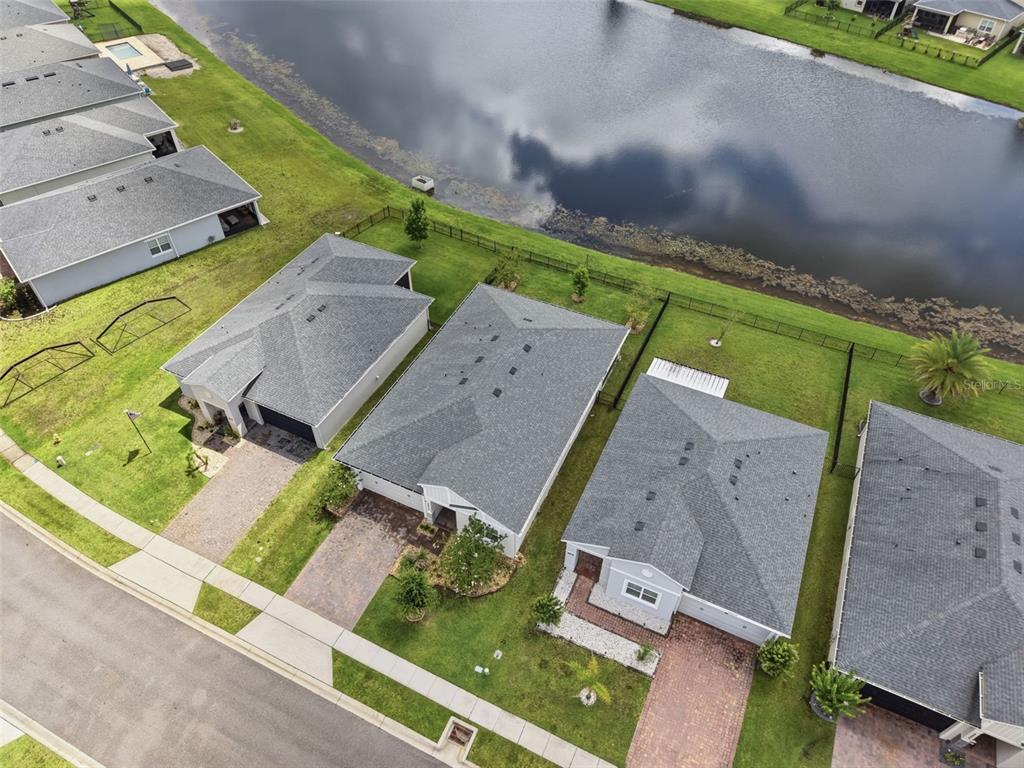 An aerial view shows several suburban houses with gray roofs situated along a pond — 5576 ESTERO LOOP, PORT ORANGE, FL