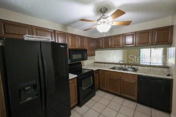 A kitchen features wood cabinets, black appliances, a ceiling fan, and a tiled floor — 1155 THAYER STREET, SAFETY HARBOR, FL