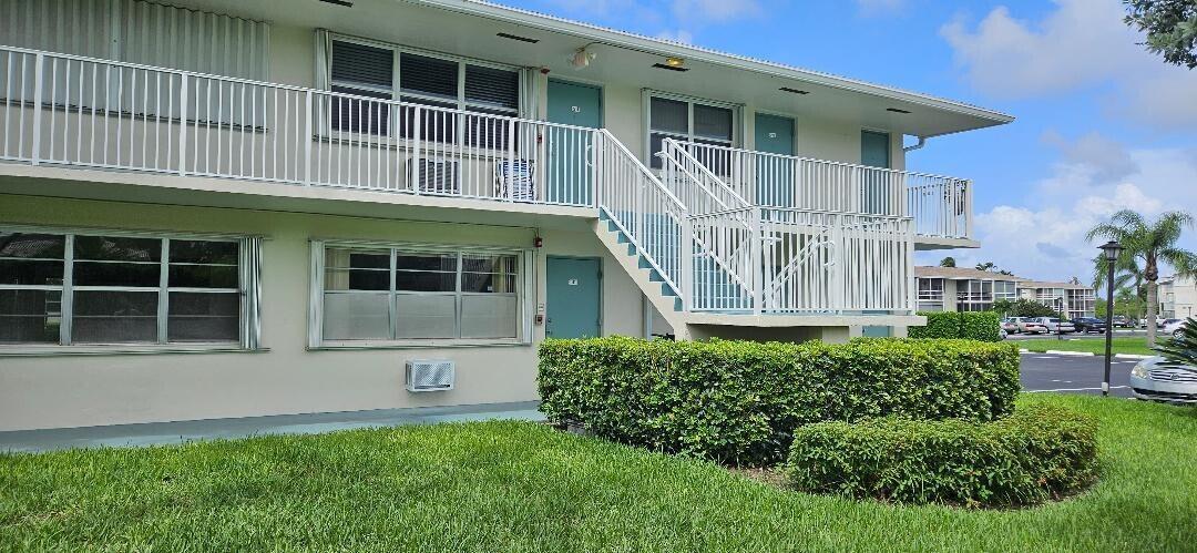 A two-story apartment building features white exterior walls, metal railings, and a central outdoor staircase — 880 W Horizons # 111, Boynton Beach FL 33435, BOYNTON BEACH, FL