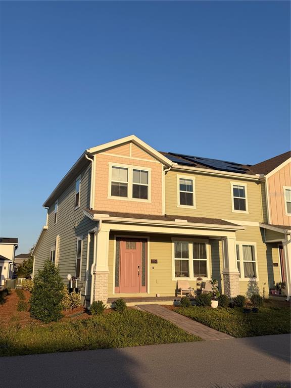 A two-story house with light green siding, a pink front door, and a covered porch — 2953 VOYAGER AVENUE, ST CLOUD, FL