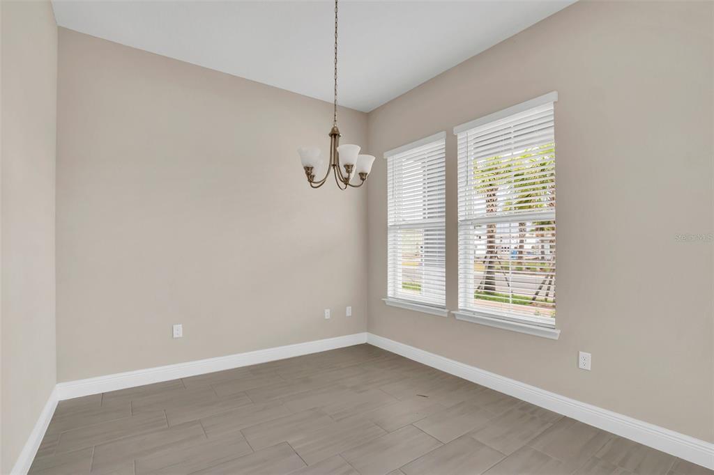 A dining room with light beige walls, gray tile flooring, and a hanging chandelier — 2953 VOYAGER AVENUE, ST CLOUD, FL