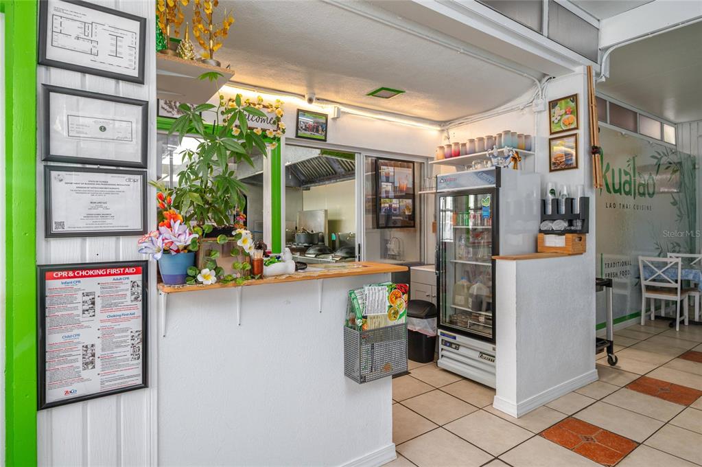 A restaurant service counter features a menu display, a refrigerator, and wall-mounted safety certificates — 114 W CENTRAL AVENUE, LAKE WALES, FL