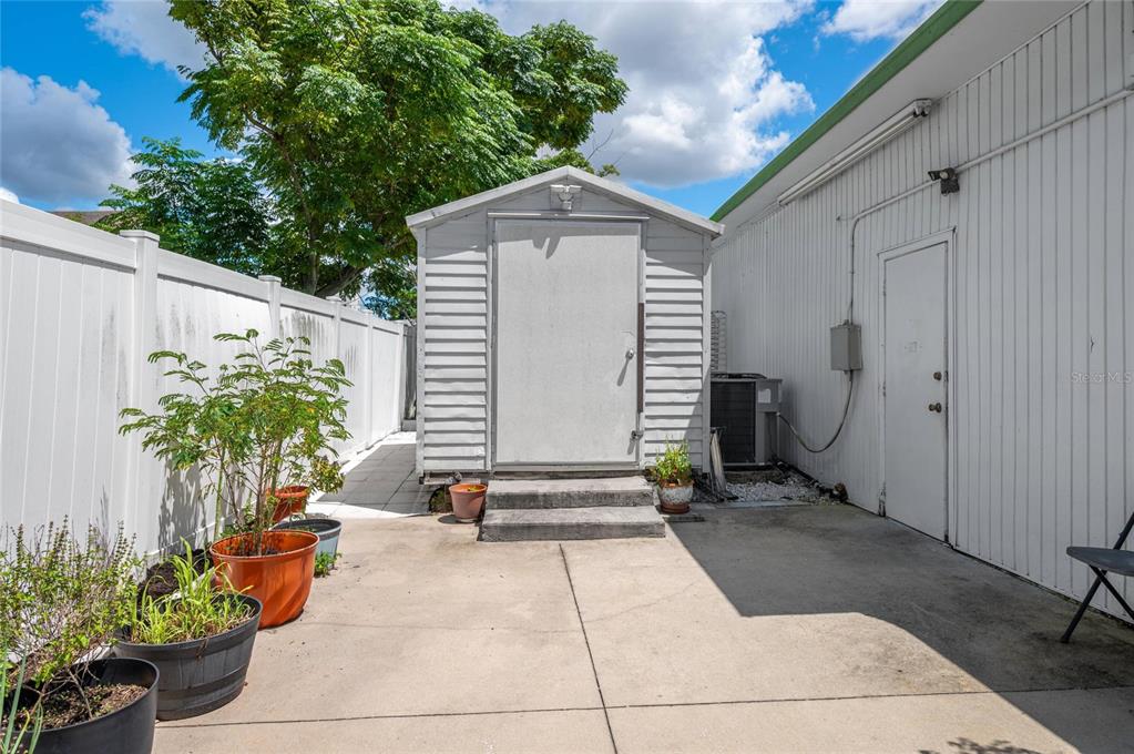 A small shed sits on a concrete patio next to a white building and fence — 114 W CENTRAL AVENUE, LAKE WALES, FL