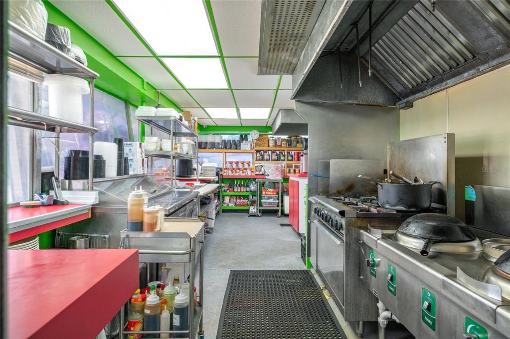A commercial kitchen features stainless steel appliances, a large exhaust hood, and green wall accents — 114 W CENTRAL AVENUE, LAKE WALES, FL