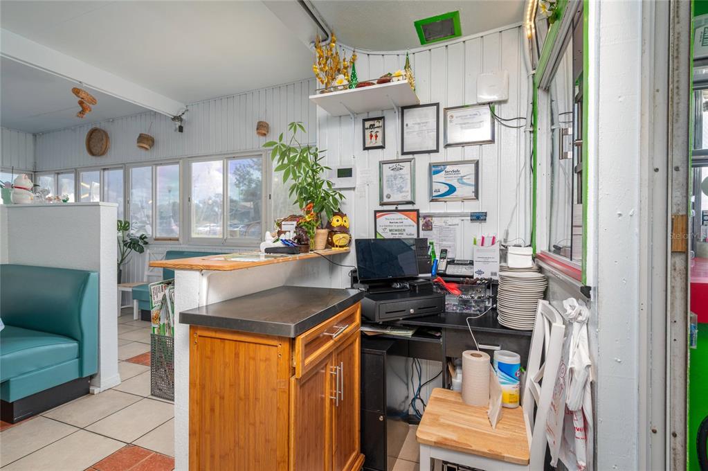 A restaurant service counter features a wooden cabinet, a point-of-sale system, and framed wall certificates — 114 W CENTRAL AVENUE, LAKE WALES, FL