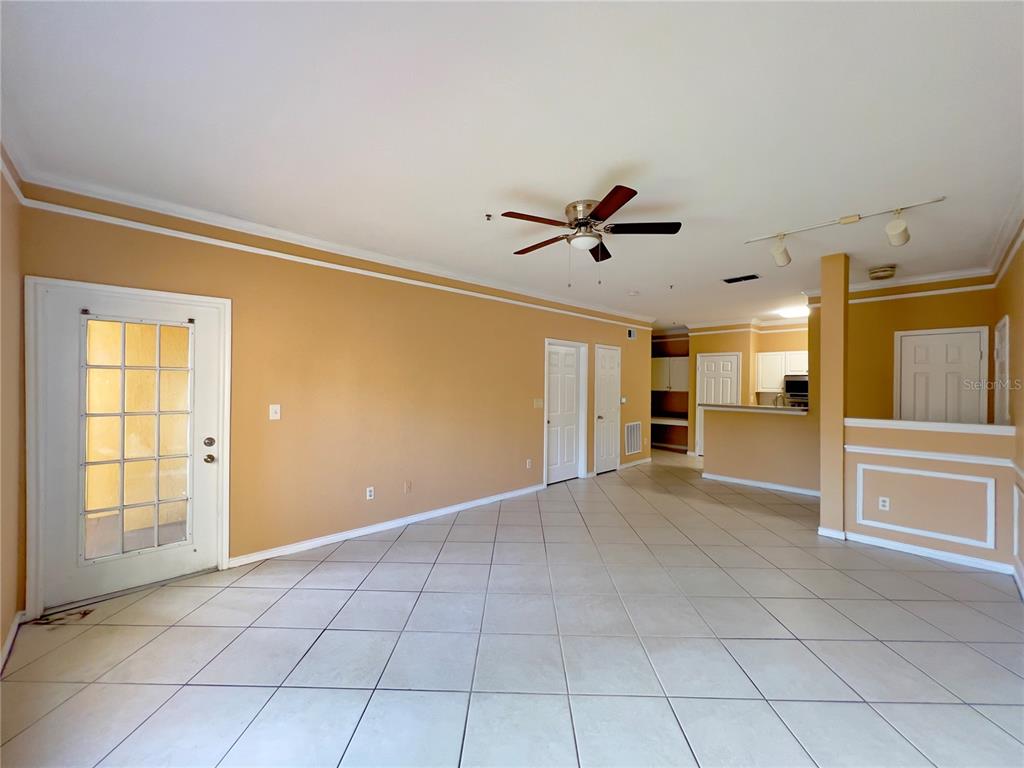 A spacious living area features tan walls, white tile flooring, and a ceiling fan — 4309 BAYSIDE VILLAGE DRIVE UNIT 102, TAMPA, FL