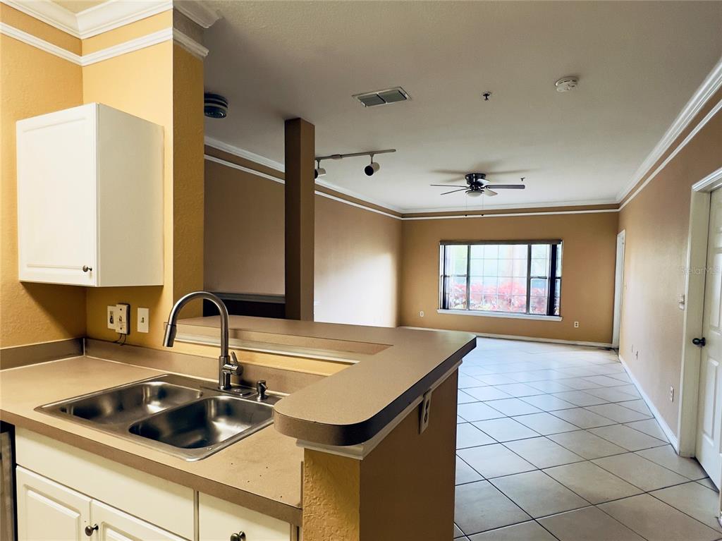 A kitchen sink and counter overlook a living area with tile floors and a window — 4309 BAYSIDE VILLAGE DRIVE UNIT 102, TAMPA, FL