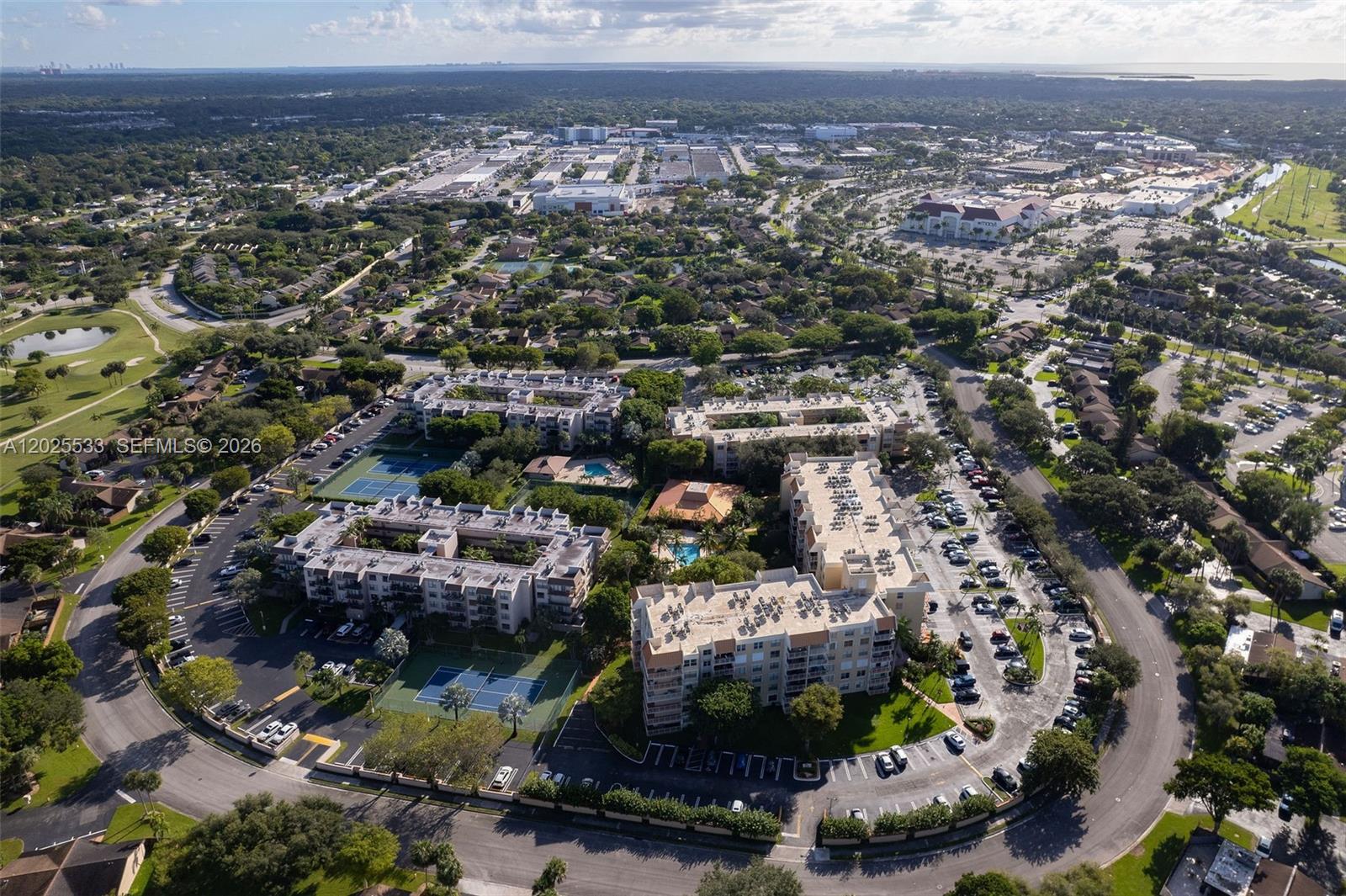 An aerial view shows multi-story apartment buildings, tennis courts, and parking lots in a suburban area — 13120 SW 92nd Ave # B505, Miami FL 33176, MIAMI, FL
