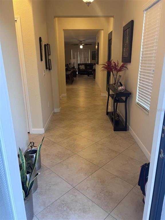 A tiled entryway leads through a hallway into a living area with a ceiling fan — 14719 SPEER LAKE DRIVE, WINTER GARDEN, FL