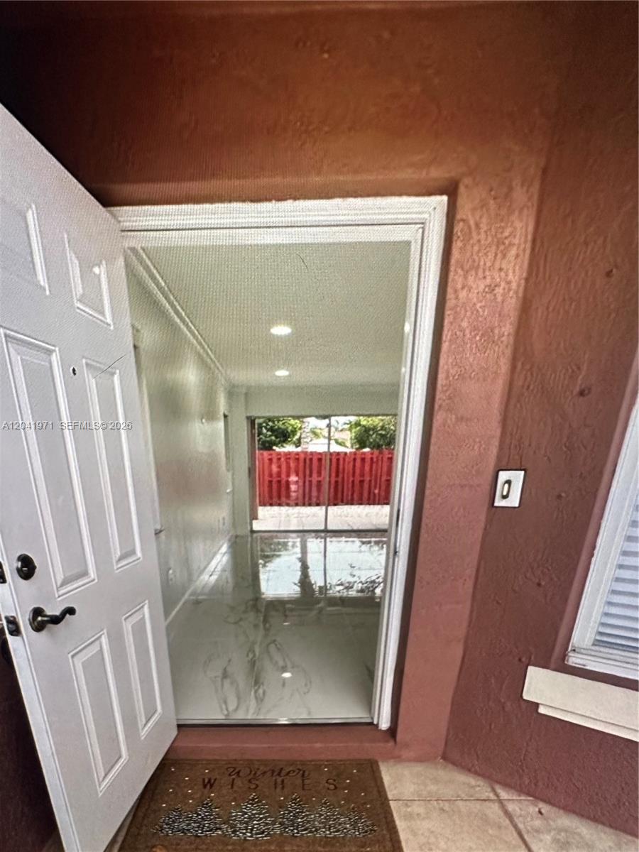 An open front door reveals a bright interior with white tile floors and sliding doors — 7001 SW 164th Ct # 0, Miami FL 33193, MIAMI, FL