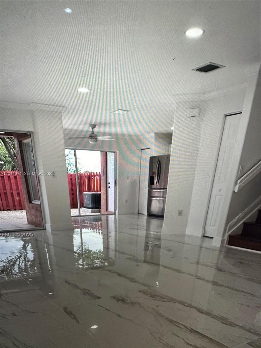 A bright living area features white marble-look tile flooring, a sliding glass door, and stairs — 7001 SW 164th Ct # 0, Miami FL 33193, MIAMI, FL