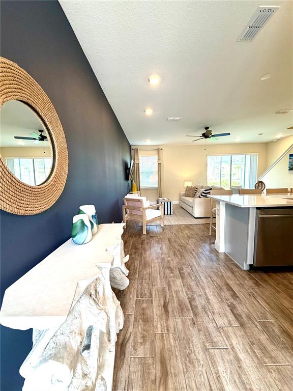 A living room and kitchen area features a dark accent wall, wood-look tile, and furniture — 3008 CARIBBEAN SOUL DRIVE, KISSIMMEE, FL