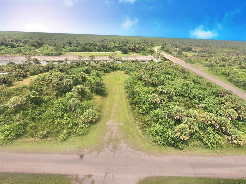 An aerial view shows a grassy path leading through a wooded lot toward a canal — SNOWBANK COURT, NORTH PORT, FL