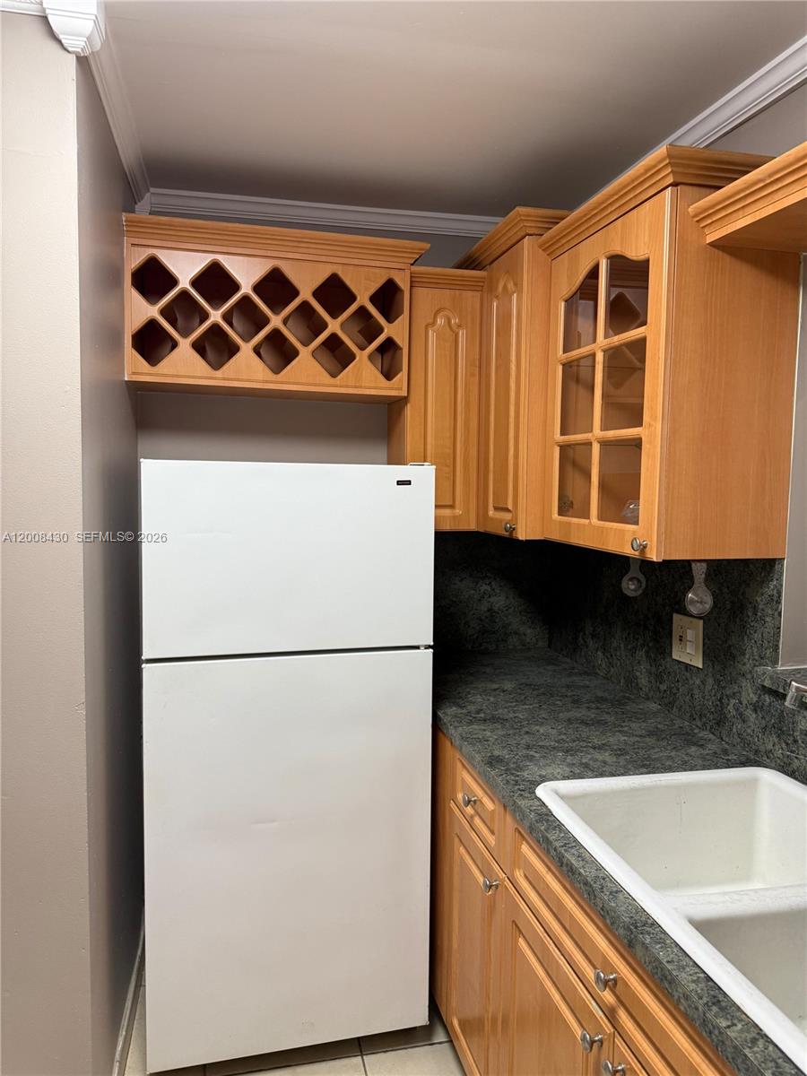A kitchen features wood cabinets, a white refrigerator, and a dark countertop with a sink — NORTH MIAMI, FL