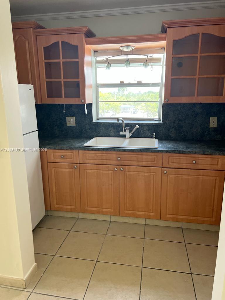 A kitchen features light wood cabinets, a white double-basin sink, and dark countertops — NORTH MIAMI, FL