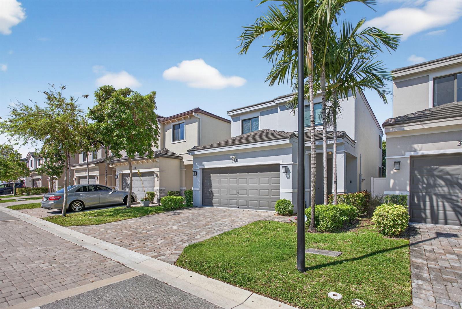 A two-story suburban house with a gray garage and a paved driveway under a blue sky — 325 NW 33rd Lane, Pompano Beach FL 33069, POMPANO BEACH, FL